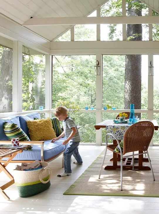 a contemporary sunroom with stylish furniture, bright upholstery, rugs and a basket is a cool space to be