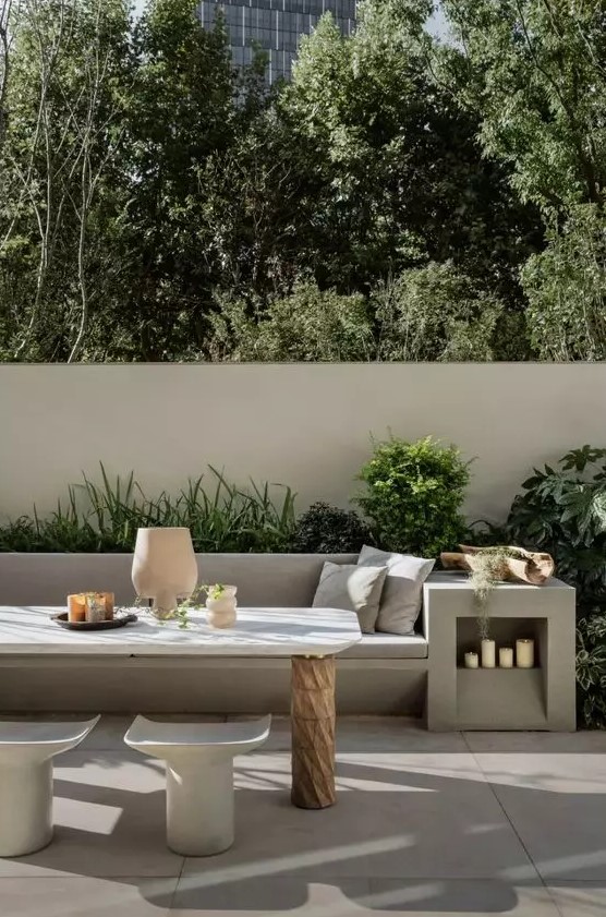 a contemporary terrace with a concrete sofa and a side table, neutral upholstery, a wood and stone table and matching chairs