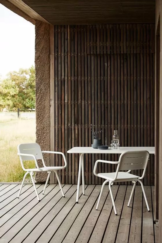 a contemporary terrace with a wooden deck and a roof clad with wooden slats, white metal dining furniture for a contrast