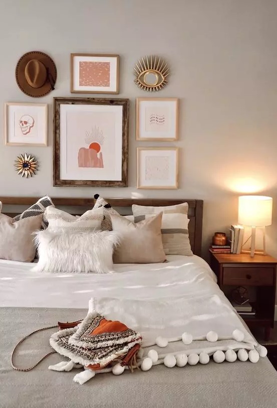 a cool boho bedroom with a stained bed and nightstands, a bright boho gallery wall, neutral bedding and a pompom blanket