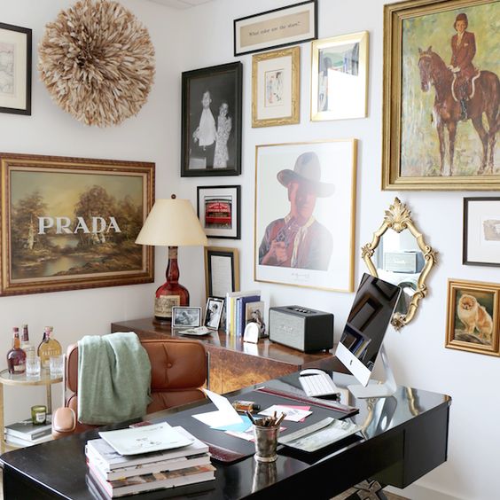 a cool home office with a sleke and glossy black desk, a brown leather chair, a two wall gallery wall and a small home bar