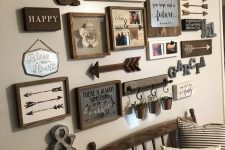 a cool vintage rustic gallery wall with arrows, monograms, various artworks and signs in frames, greenery in buckets