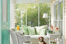 a cute neutral vintage sunroom with a mint ceiling, white wicker furniture, printed pillows and a minty door