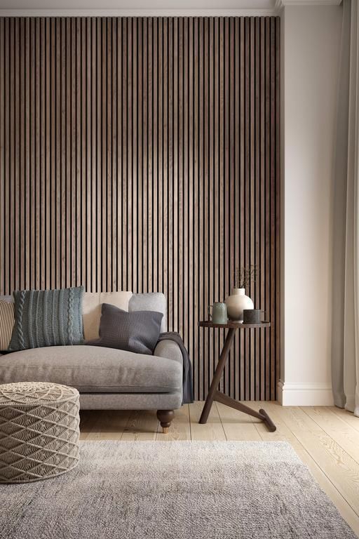 a delicate contemporary space with a wood slat accent wall, a grey sofa with lots of pillows, a side table and a pouf