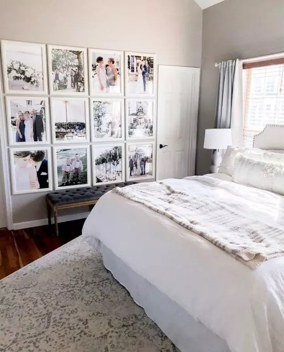 a farmhouse bedroom with a light colored bed with neutral bedding, a stylish grid gallery wall and a black leather bench