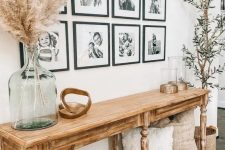 a farmhouse entryway with a vintage wooden console and a chic black and white gallery wall with white matting and black frames