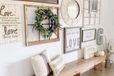 a farmhouse gallery wall with a clock in a thick frame, a window frame with a wreath, some plaques and metal monograms is cute