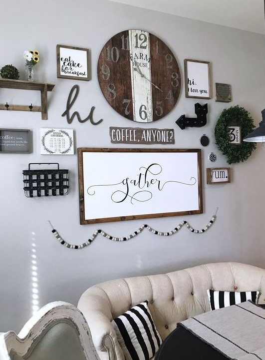 a farmhouse gallery wall with a shelf, a greenery wreath, arrows, a wooden clock, some signs in frames and a wooden bead garland is cool