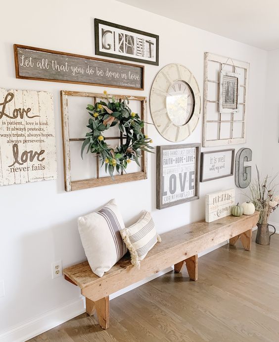 a farmhouse gallery wall with signs and artwork, a window frame, a greenery and bloom wreath plus a clock in the center