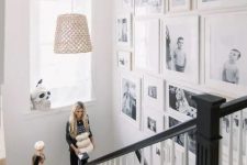 a free form gallery wall with black and white family pics and white frames si a very chic and stylish idea for any space