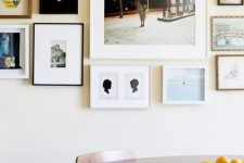 a free form gallery wall with thin black, white and wooden frames and white matting but mismatching black and white and color art