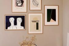a free form modern gallery wall with thin gilded frames and graphic artworks for a chic modern touch in the space
