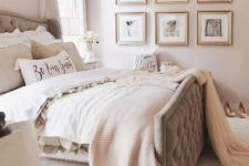 a glam bedroom with light pink walls, a grey upholstered bed with neutral bedding, a grid gallery wall and another one over the headboard