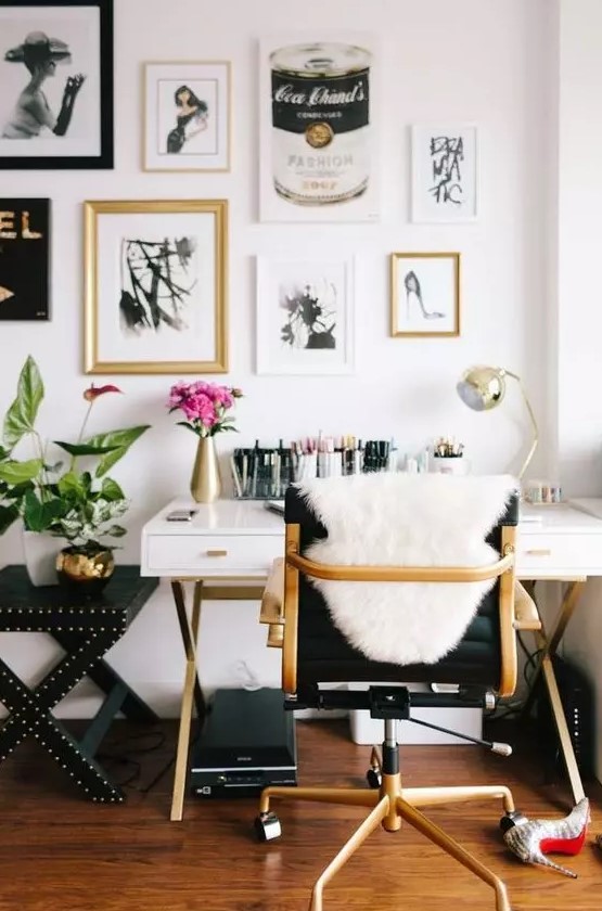 a glam home office with a chic white and gold desk, a black chair, a lovely blakc, white and gallery wall plus blooms and gold touches