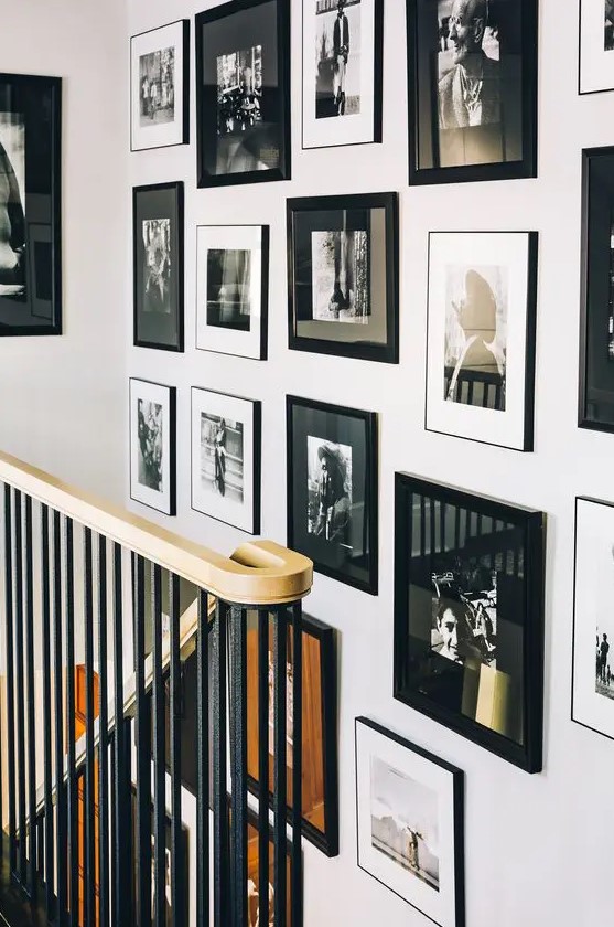 a gorgeous free form gallery wall with mismatching black frames, black and white matting and chaotically placed artworks
