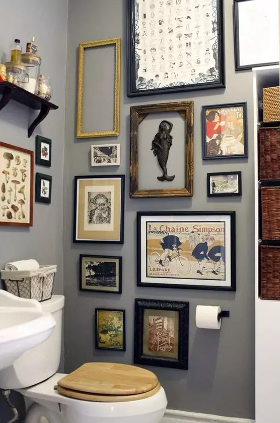 a grey bathroom with a catchy vintage gallery wall, white appliances and baskets for storage is a lovely space