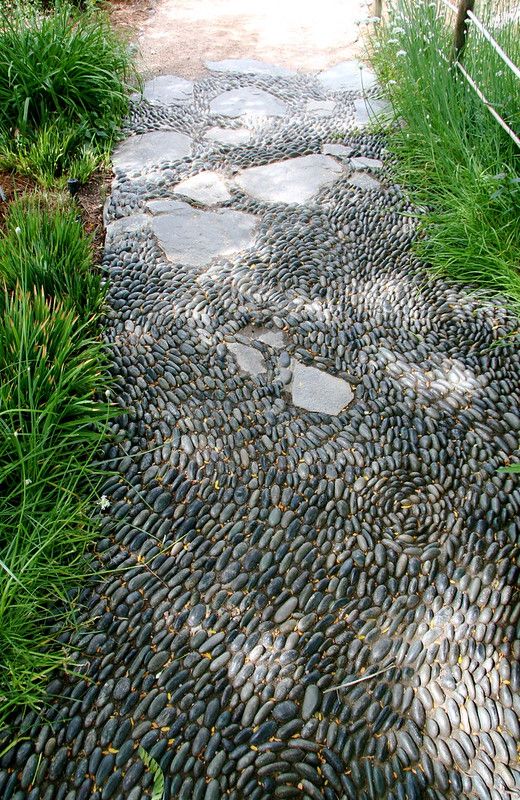 a grey pebble path with lots of rocks, with greenery lining it up is a great solution for a nature-infused modern space