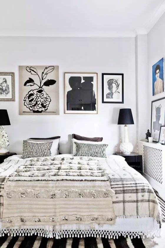 a high contrasting bedroom with a bed and printed bedding, several gallery wall, printed rugs and black table lamps