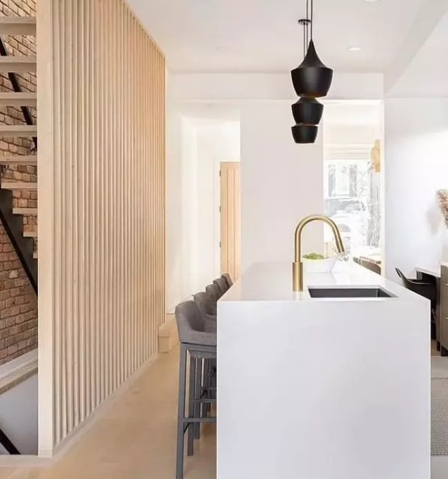 a light-stained wood slat accent wall that hides a staircase and gives more harmony to the kitchen space