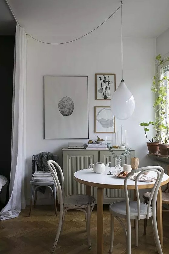a lovely Scandinavian dining zone with a grey cabinet, a round table and vintage chairs, a mini gallery wall and some greenery