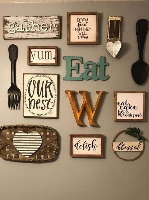 a lovely kitchen gallery wall with letters and monograms, signs in frames, pretty cutlery and a tiny wreath with greenery