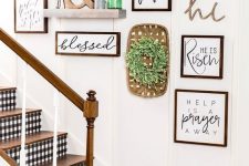 a lovely rustic gallery wall with signs in stained frames, a greenery wreath, a shelf with potted grass and an ampersand and a green bottle