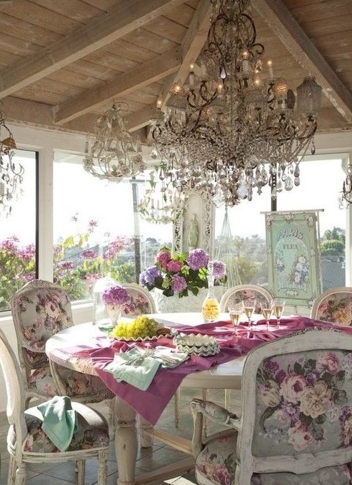 a luxurious vintage sunroom with windows all around, crystal chandeliers, refined furniture and floral chairs, floral artworks