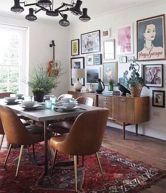 a mid-century modern dining space with a rich-stained credenza, a concrete table and leather chairs, a bold rug and a bright gallery wall