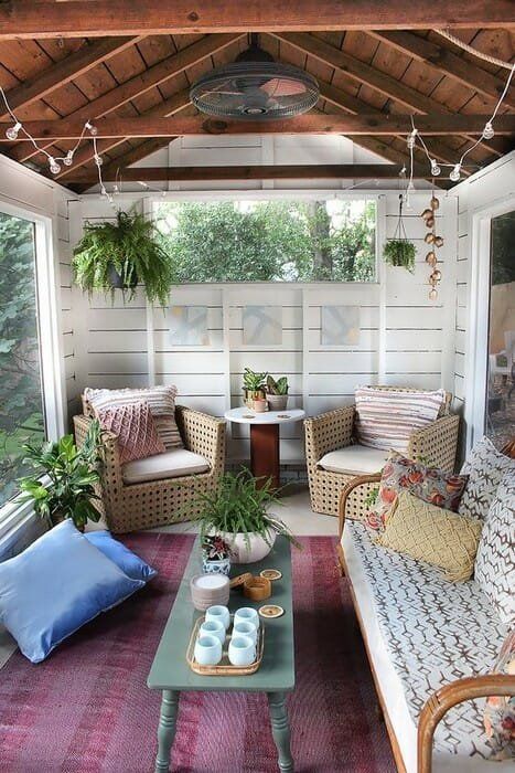 a mid century modern to boho surnoom with rattan and woven furniture, with printed pillows and a bold rug and some potted plants