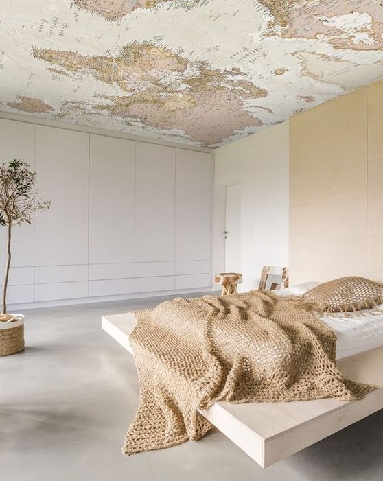 a minimalist bedroom with a map on the ceiling to dream where to go while lying in the bed