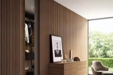 a minimalist space with a wood slat accent wall, a floating storage unit with lights, a glazed wall with a garden view