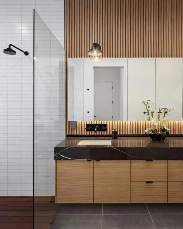 a modern bathroom with white skinny tiles, a light stained floating vanity and a wood slat wall, a mirror and large scale tiles on the floor