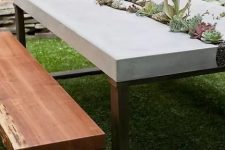 a modern outdoor dining space with a concrete and metal table, wood and metal benches and succulents growing in the table