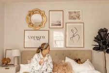 a neutral bedroom with a grey upholstered bed, neutral furniture, a chic gallery wall over the headboard and a creamy nightstand