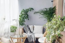 a neutral boho sunroom with grey walls, rattan furnitur,e potted plants, a glass coffee table and a woven pendant lamp