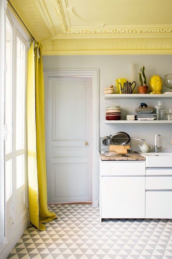 a neutral kitchen accented with a yellow ceiling with stucco, a yellow curtain and a printed rug plus some yellow accents