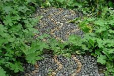 a pebble garden path with black and neutral pebbles with a swirl pattern and curves