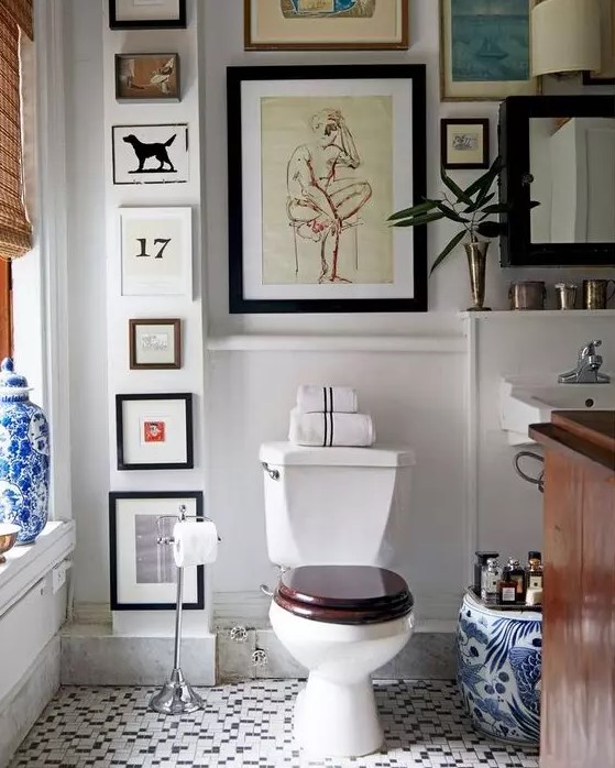 a pretty bathroom with blue and white tiles, a dark-stained vanity, a woven curtain and a gallery wall that takes all the blank space here