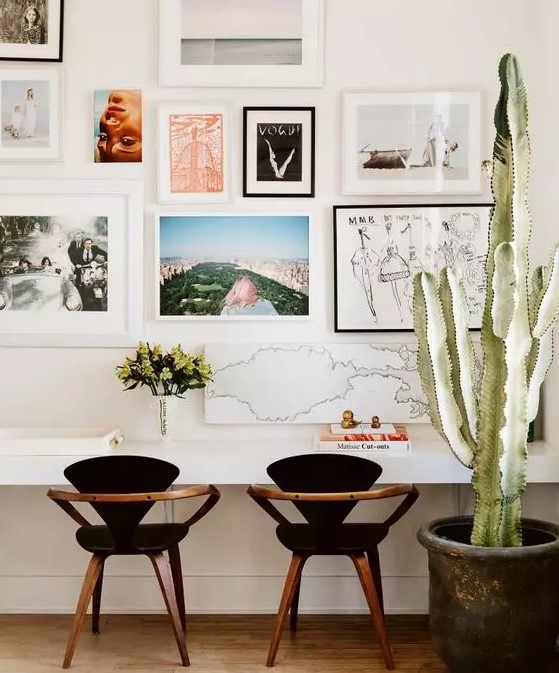a pretty mid-century modern home office with a wall-mounted shared desk, black chairs, a bright gallery wall and a potted cactus