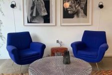 a quirky space with cobalt blue chairs, a striped round table, a colorful rug and a black and white gallery wall