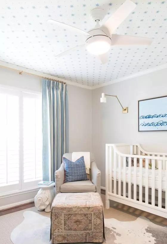 a rather neutral blue and white kid's room made cooler with a printed wallpaper ceiling that adds catchiness to the room