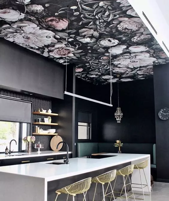 a refined moody kitchen with black walls and cabinets, a dark floral wallpaper ceiling, a black and white kitchen island