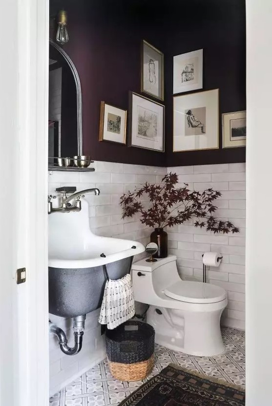 a refined moody mudroom with purple walls and white tiles, a black wall mounted sink, a basket and some bulbs and lights