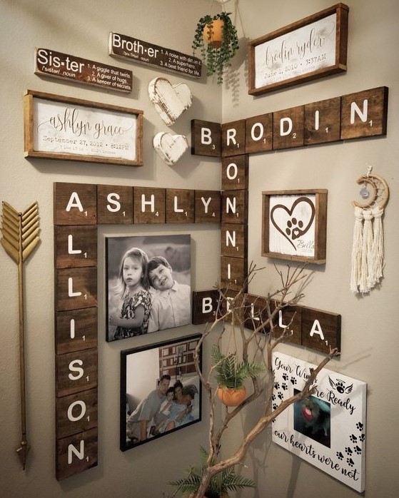 a rustic and boho gallery wall with wooden letters, signs in frames, some branches, arrows, tassels and potted greenery