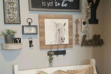 a rustic gallery wall with a chalkboard sign in a frame, artworks, monograms, arrows, a clock and various potted plants