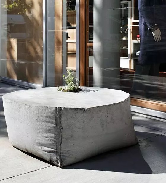a sack-shaped outdoor concrete table with a planter in the center is a unique solution that looks fresh