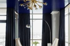 a shiny navy ceiling is a cool way to add a touch of color and a moody feel to the monochromatic bedroom