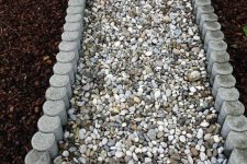 a simple pebble garden path lined up with concrete borders is a cool idea for a modern space, it’s pretty easy to compose and all the pebbles will be kept in place