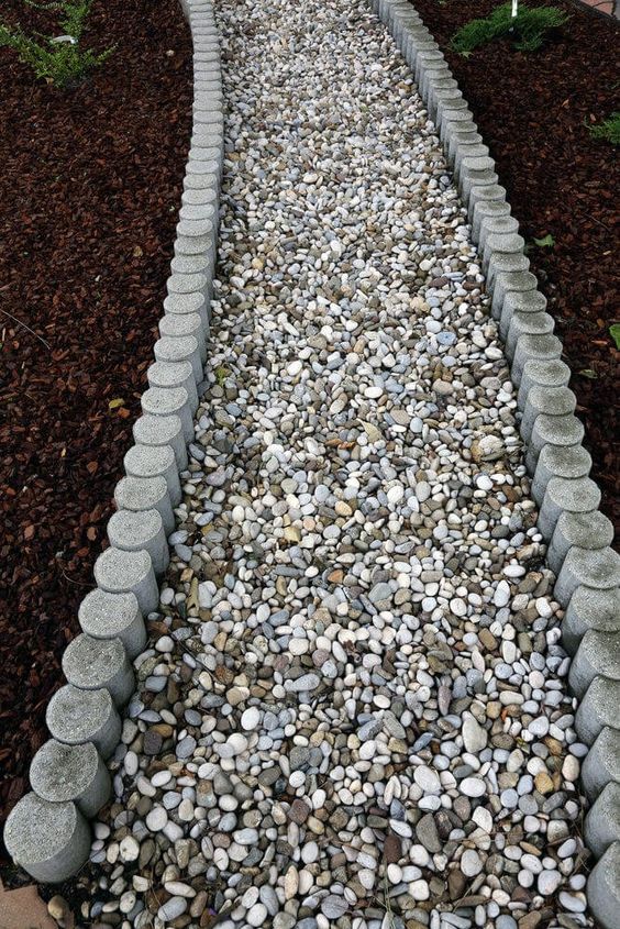a simple pebble garden path lined up with concrete borders is a cool idea for a modern space, it's pretty easy to compose and all the pebbles will be kept in place