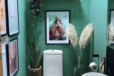 a small yet lovely emerald mudroom with a gallery wall, white appliances, pampas grass and a cactus, some candles